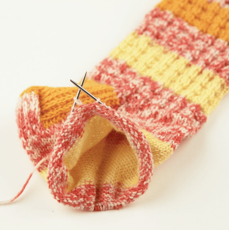 addiSockwonder Lace circular knitting needle 25cm - 710-7 - Knitted multicolored sock with a needle on a white background