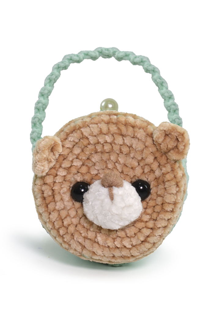 Círculo Amigurumi Pelúcia – Polyester Chenille Yarn (131 m / 85 g) - A small crocheted teddy bear face handbag with a mint green braided handle, featuring a light brown textured body, black bead eyes, and a white plush nose on a white background.