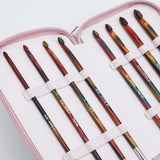 KnitPro Symfonie 2 Afghan Tunisian crochet hook set - A set of colorful crochet hooks stored in a light pink zippered case with white elastic loops. The hooks have a marbled, multicolor pattern with shades of red, green, orange, and black, and some white text is visible on the handles.