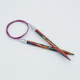 KnitPro Symfonie 2 fixed circular knitting needles with swivel cable, 60 cm - Circular knitting needles with a colorful wood-grain pattern in green, red, and orange, featuring silver metal tips and a purple cable, shown on a light gray background.