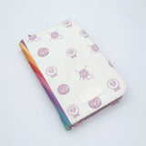 KnitPro Symfonie 2 Mini interchangeable needle set, 5 cm - A zippered notebook or planner cover with a cream-colored faux leather exterior decorated with a pattern of purple yarn balls and sheep, and a colorful striped edge showing rainbow hues.